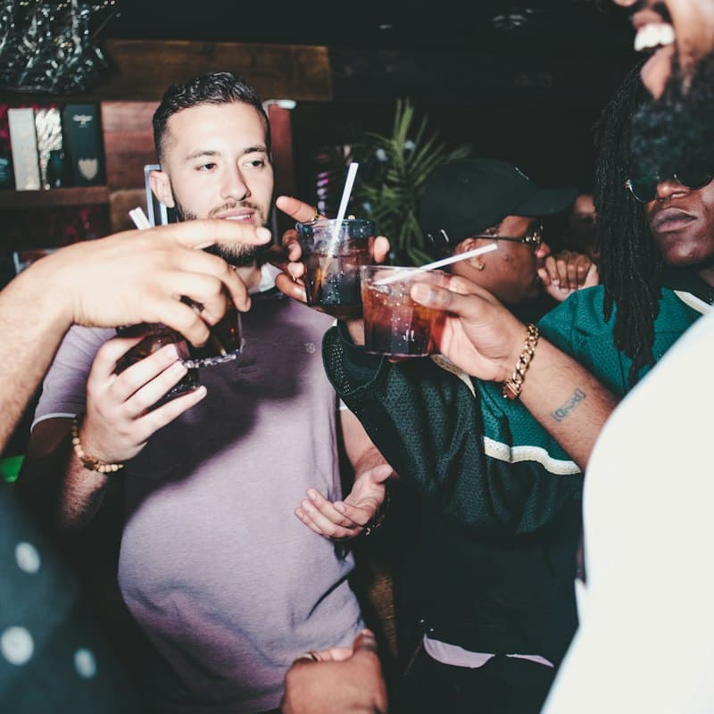 A group toasting with dark drinks in a bar