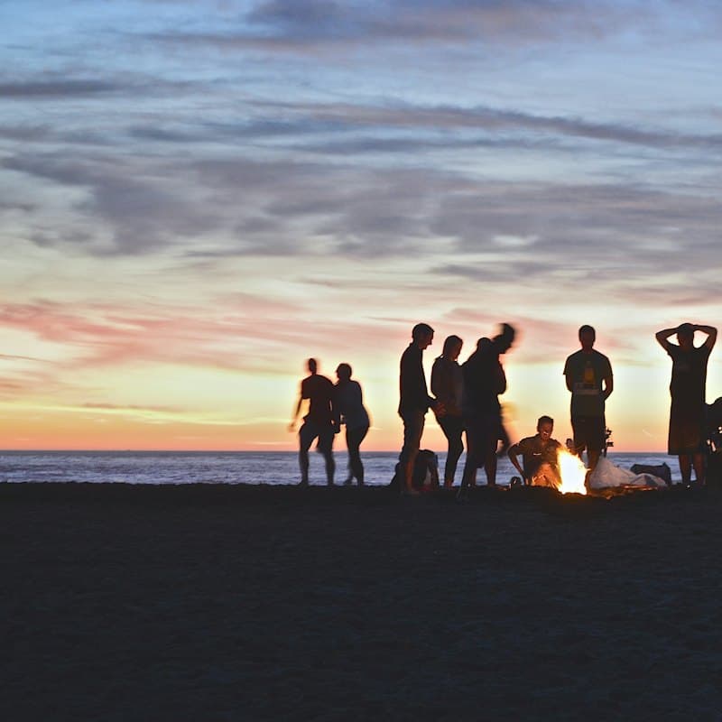 Friends around a beach campfire at sunset
