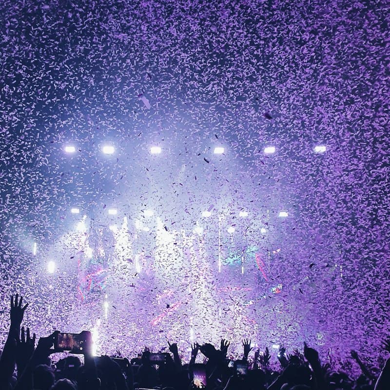 Purple confetti falling over a concert crowd