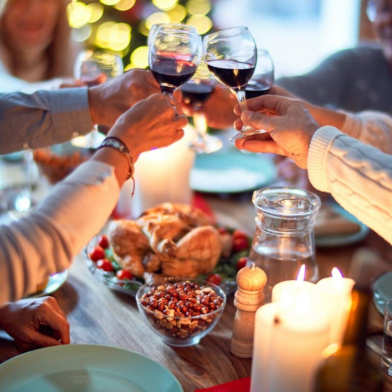 People toasting with red wine over a festive dinner table