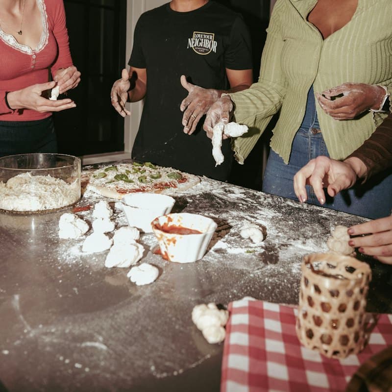 Friends making pizza together at a kitchen counter