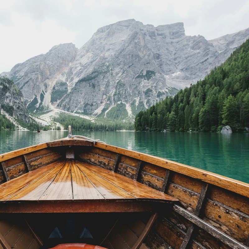 A wooden boat on a turquoise lake under mountain peaks