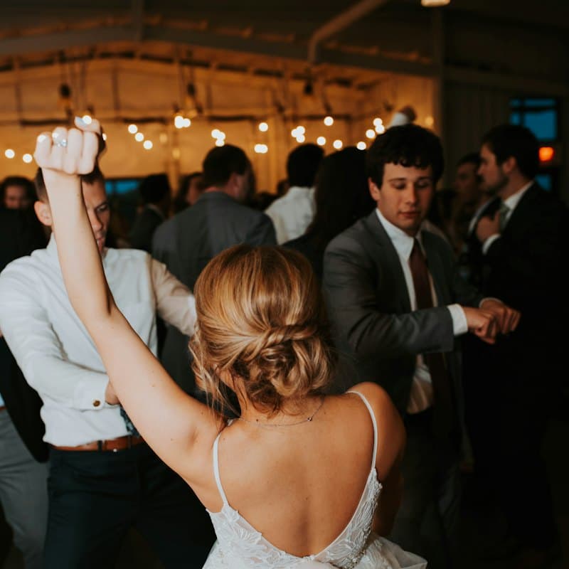 Guests dancing at a wedding reception under string lights