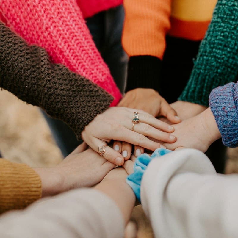 A group stacking hands in colourful sweaters