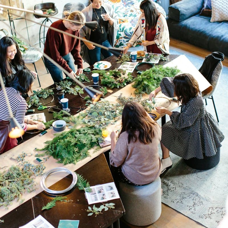 People crafting with greenery at a workshop table